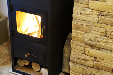 burning metal fireplace with wood at the stone wall