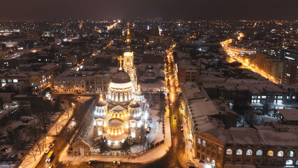 Holy Annunciation Cathedral illuminated in winter snowy night lights. Aerial view Kharkiv city orthodox church sight, Ukraine.  Main city landmark from air.