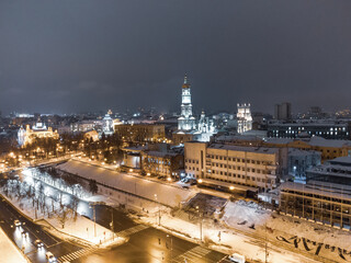 Obraz premium Winter snowy evening lights illuminated city aerial landscape. Dormition Cathedral, Serhiivskyi Maidan in Kharkiv downtown, Ukraine