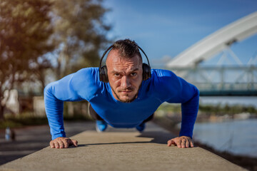 Fototapeta premium Young handsome man training hard. Man doing sports outside. Outdoors recreation, stretching and training fit body