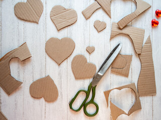 Scissors, cardboard.The process of cutting hearts out of cardboard.