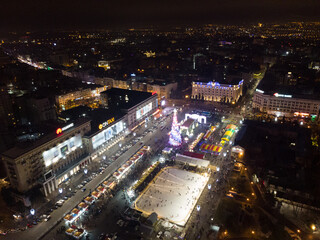Fototapeta na wymiar Freedom Svobody Square (Kharkiv) aerial view at night with New year holidays and Christmas tree decorations with colorful illumination in city center recreation area.