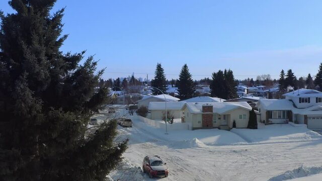 aerial reveal panout of snow covered winter town of low rise quant cozy white bed in breakfast dettached homes brick rectangular chimney and snowed in roads cars paths with tall fraser fir trees 2-2