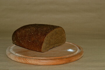 Bread on wooden round board on a brown background