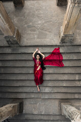 Portrait of beautiful Indian girl in heritage stepwell wearing traditional Indian red saree, gold...