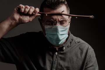 a man in a medical mask and round glasses, with a magic wand on a dark background.