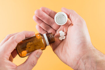 close-up of hands dispensing tablets from pill bottle, medication concept