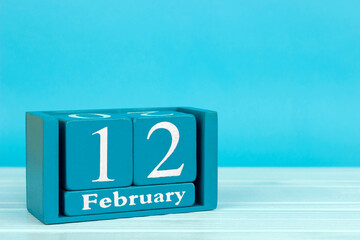 wooden calendar with the date of February 12 on a blue wooden background	