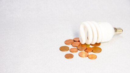 Close-up of a led light bulb on various coins on white background. Concept of energy saving at home.