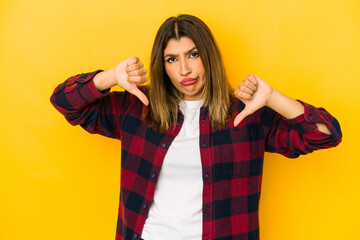Young indian woman isolated on yellow background showing thumb down, disappointment concept.