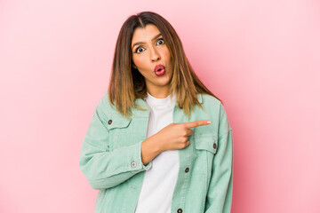 Young indian woman isolated on pink background pointing to the side