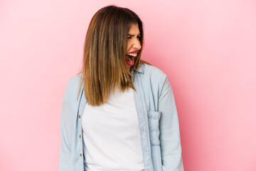 Fototapeta premium Young indian woman isolated on pink background shouting very angry, rage concept, frustrated.