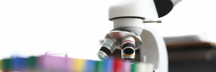 A microscope is standing next to empty test tubes. Accurate measurement results and chemical control analyzes