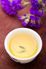 A cup of Chinese tea with a bunch of purple flower