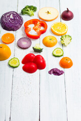 sliced fruit and vegetable circles on white wood table