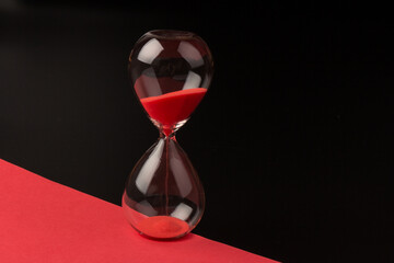 Crystal hourglass on black and red background as a concept of passing time for business term,...