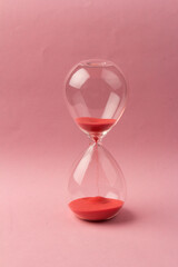 Crystal hourglass on pink background as a concept of passing time for business term, urgency and...