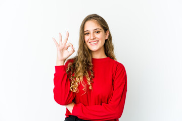 Young caucasian woman winks an eye and holds an okay gesture with hand.