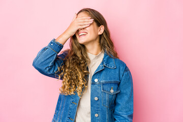 Young caucasian woman covers eyes with hands, smiles broadly waiting for a surprise.