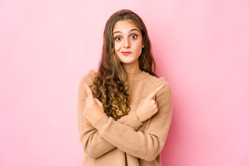 Fototapeta premium Young caucasian woman points sideways, is trying to choose between two options.