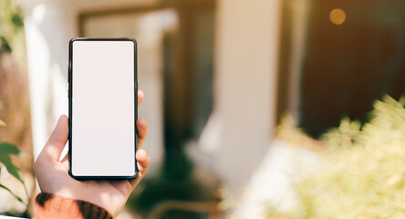 A man hand with red sweater are holding a mockup of vertical black 5g mobile smartphone with blank white screen for insert your design, digital global communicate by smart phone, clipping path include