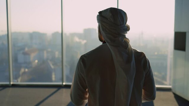 Premium Photo  An arab man, a businessman, a sheikh stands in front of a  skyscraper window. investments, business, work via the internet, online  contracts.