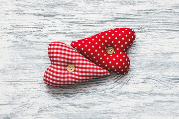 Two fabric hearts on wooden background