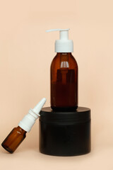 Brown glass bottle with a pump of cosmetic products framed by green leaf branches, beige background. Natural organic spa cosmetic beauty concept. Front view Mock up.