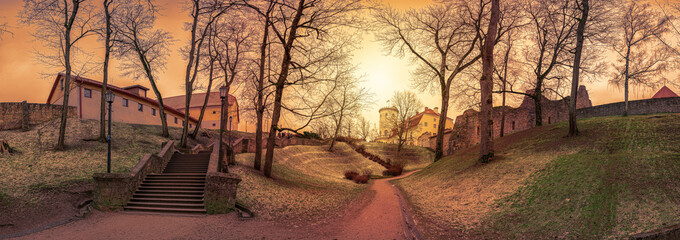 Panoramic view of sunset over medieval stone castle ruins with old stone stairs in the park