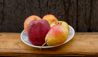 Fototapeta na wymiar beautiful juicy apples and pears on a plate in raindrops.