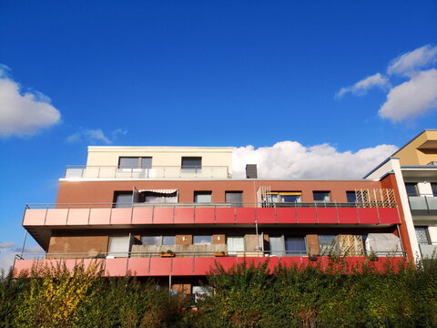 Modernes Wohnhaus in Naturfarben mit roter Balkonverkleidung vor blauem Himmel bei Sonnenschein in Bielefeld L&auml;mershagen-Gr&auml;fenhagen im Teutoburger Wald in Ostwewstfalen-Lippe