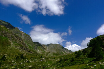 Naklejka premium green mountains with soft white clouds on the deep blue sky