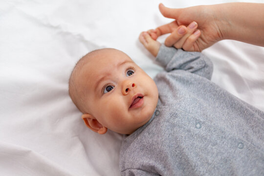 Portrait of a newborn girl. Newborn daughter grabbed mom's finger