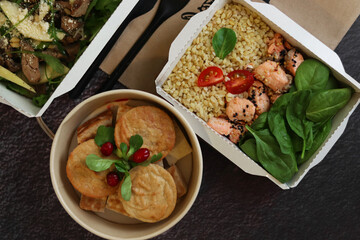 The concept of healthy food and diet, food delivery in a restaurant. Take away fitness food. Weight loss food in paper lunch boxes. 
Banana pudding and 
salmon with bulgur and spinach.