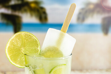 lemon drink with popsicle, beach in the background. Drink known as caipirinha in brazil, ice cream with alcohol and lemon