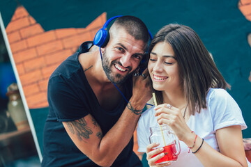 Happy loving couple with headphones sharing music in cafe