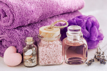 Obraz na płótnie Canvas Close up photo of Lavender aromatic bath salt, essence, soap, sponge for body and towels. Wellness Concept for spa, beauty and health salon, cosmetics store.