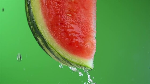 Fresh Watermelon slice over green background. Slice of ripe watermelon with dripping juice, close-up. Vegan food, diet concept. Slow motion 4K UHD video