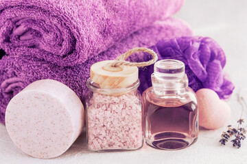 Fototapeta na wymiar Close up photo of Lavender aromatic bath salt, essence, soap, sponge for body and towels. Wellness Concept for spa, beauty and health salon, cosmetics store.