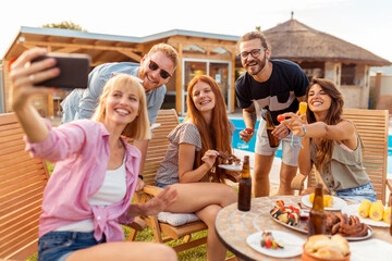 Friends taking a selfie at backyard poolside barbecue party