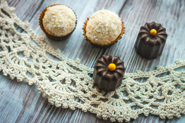 Homemade coconut and chocolate small cakes on wooden lace table