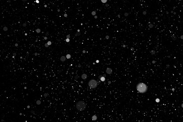 Bokeh of white snow on a black background. Falling snowflakes on night sky background, isolated for...