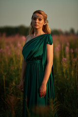 Obraz premium Young beautiful girl with a bouquet of flowers in her hands at sunset.