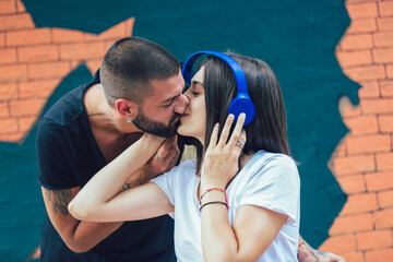 Happy loving couple with headphones sharing music in cafe