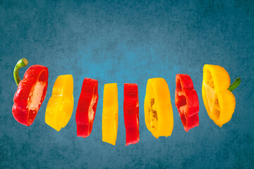 Zwei in Scheiben geschnittener roter und gelber Paprika vor einem blauen Hintergrund