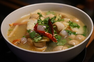 Tom Yam Kung Soup in white bowl at fish market and food stall in Bangkok, Thailand