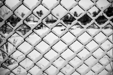 Snow lying on a chain link fence, winter background