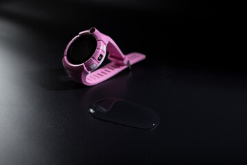 Childen's waterproof smart watch. Pink smart watch on black. Watch and water drop.