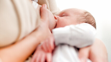 Portrait of cute little baby boy sleeping while eating milk and sucking mother's breast against big...