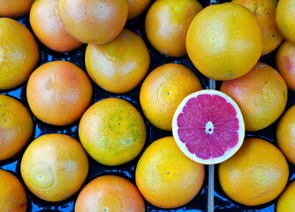 Crate of fresh grapefruit with one cut in half at a market